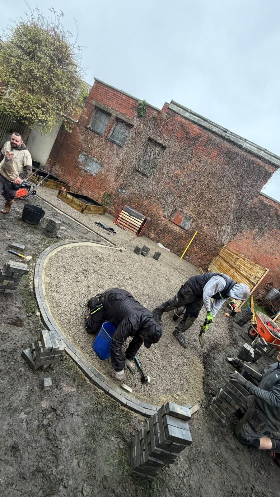 Overhead view of volunteers laying a curved block-paving edge to the central play circle