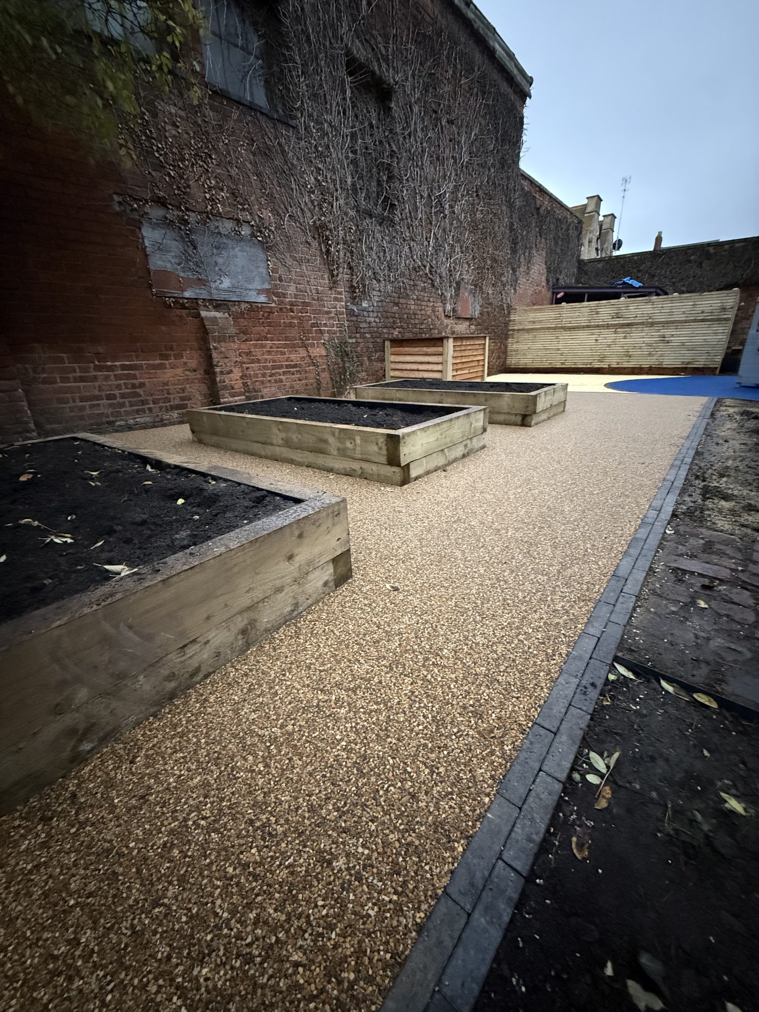 Oak sleeper raised beds beside a resin-bound path in the walled play garden