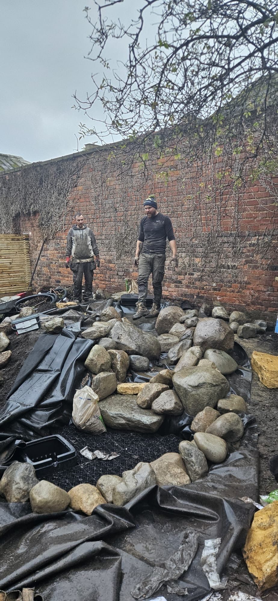 Volunteers laying the boulder base of the water feature during the play garden build