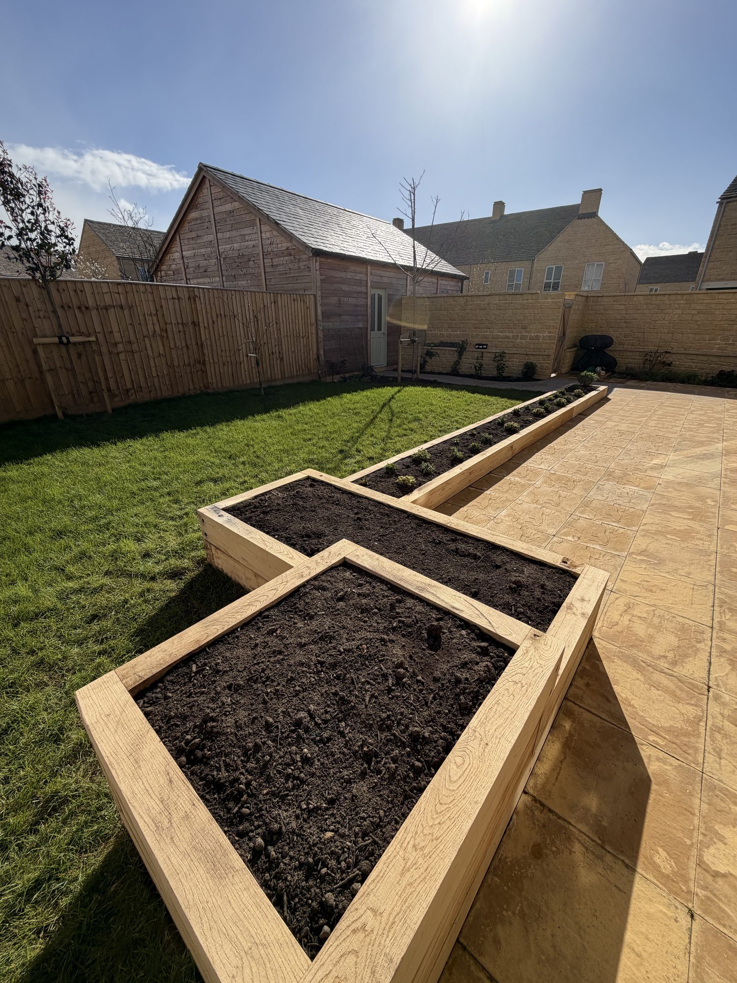 Garden overview with oak sleeper raised beds, lawn and a garden building