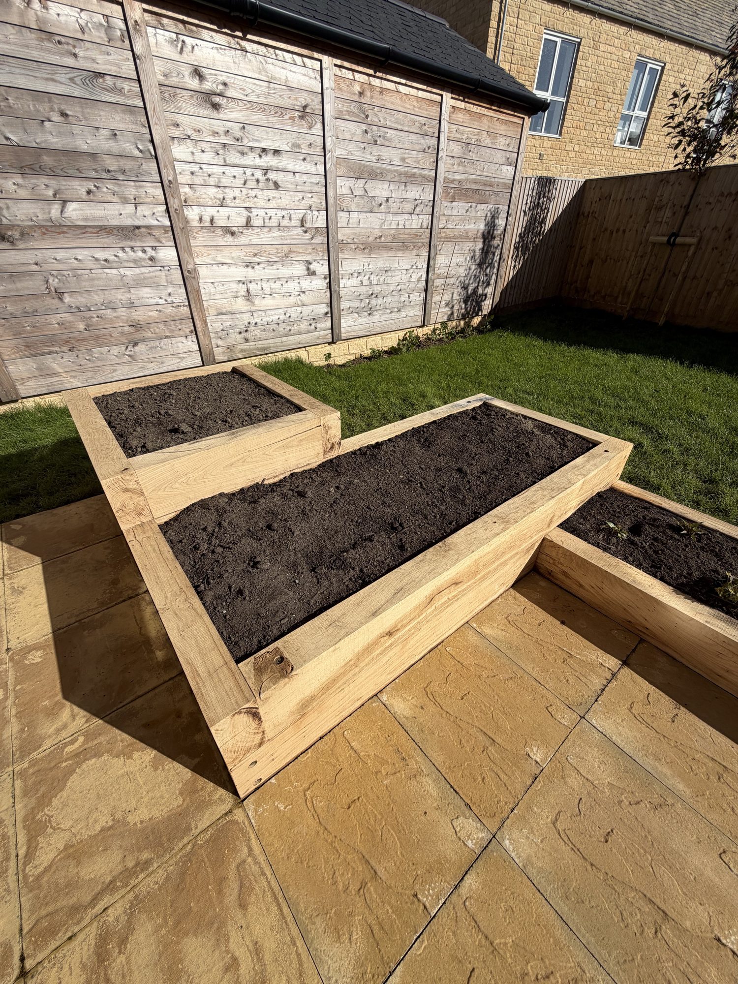 New oak sleeper raised beds on pattern-imprinted paving